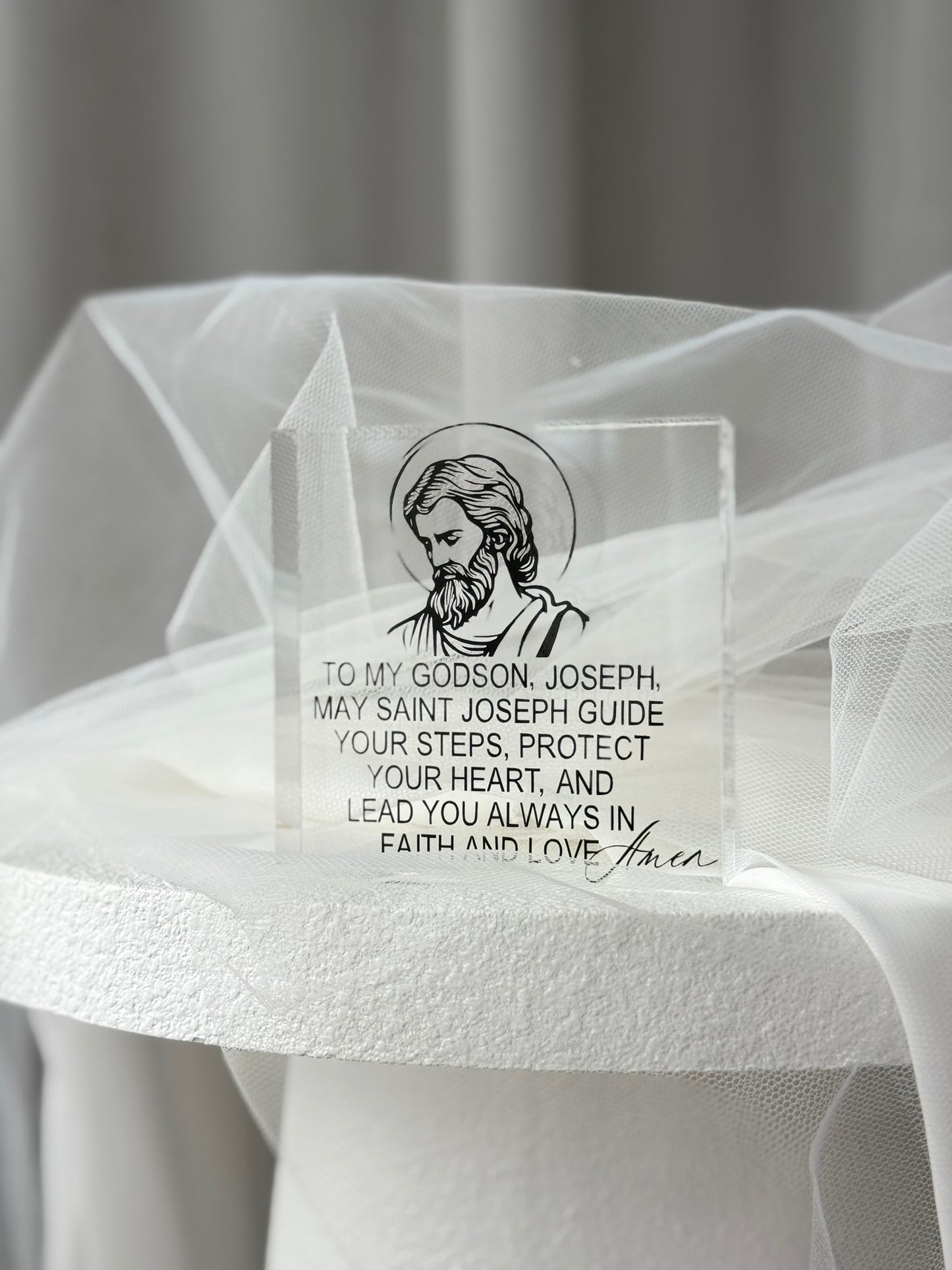Detail of clear acrylic religious plaque with saint illustration and elegant typography