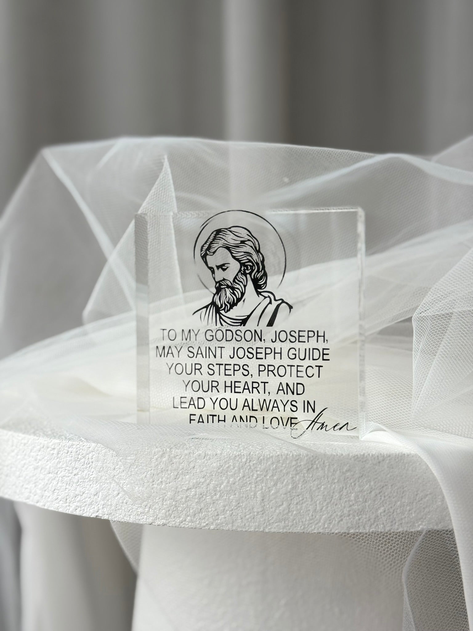 Detail of clear acrylic religious plaque with saint illustration and elegant typography